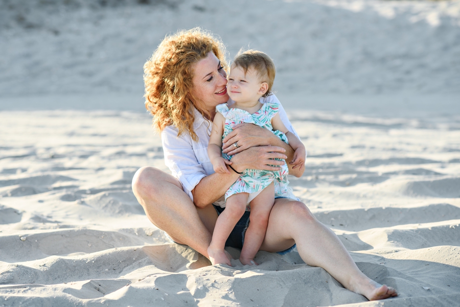 A mother holding her baby while they sit on the beach in Wildwoon, NJ during thier Family Photography Session.